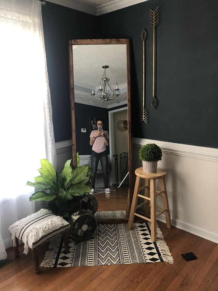 a woman taking a selfie in front of a mirror on the floor next to a stool