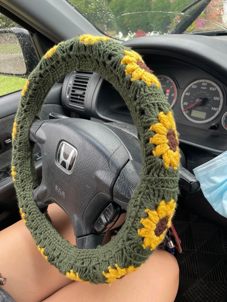 the steering wheel cover is crocheted with sunflowers and has been made from yarn