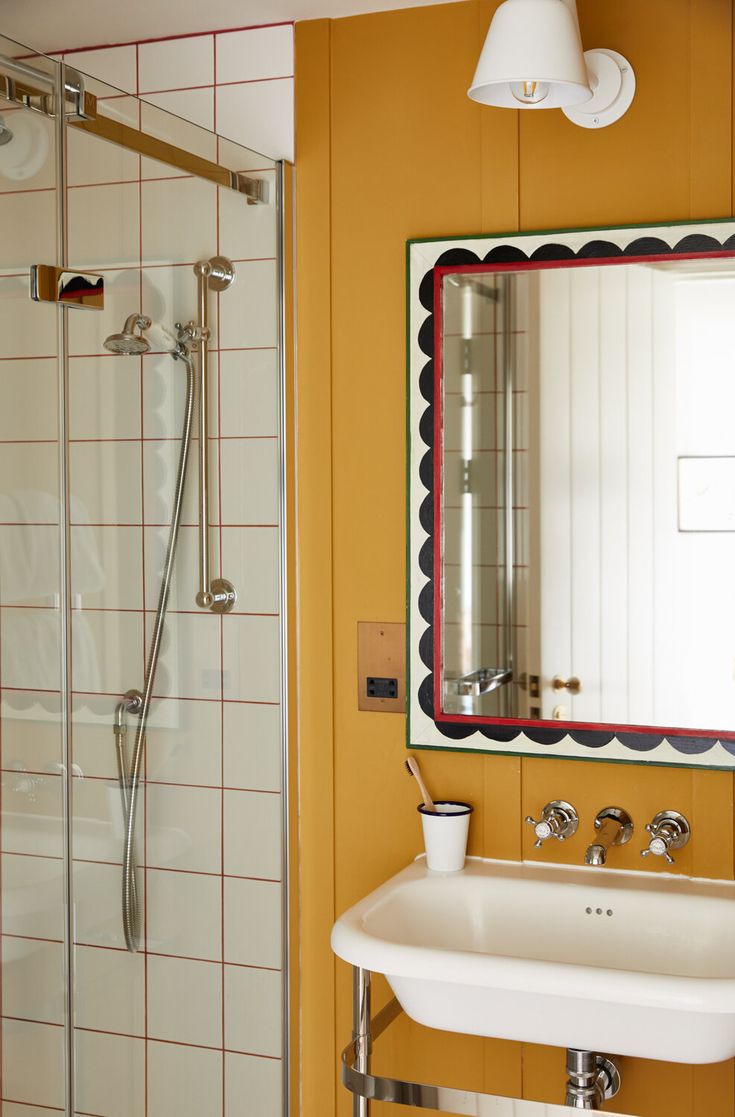 a bathroom with a sink, mirror and shower stall in the corner on the wall