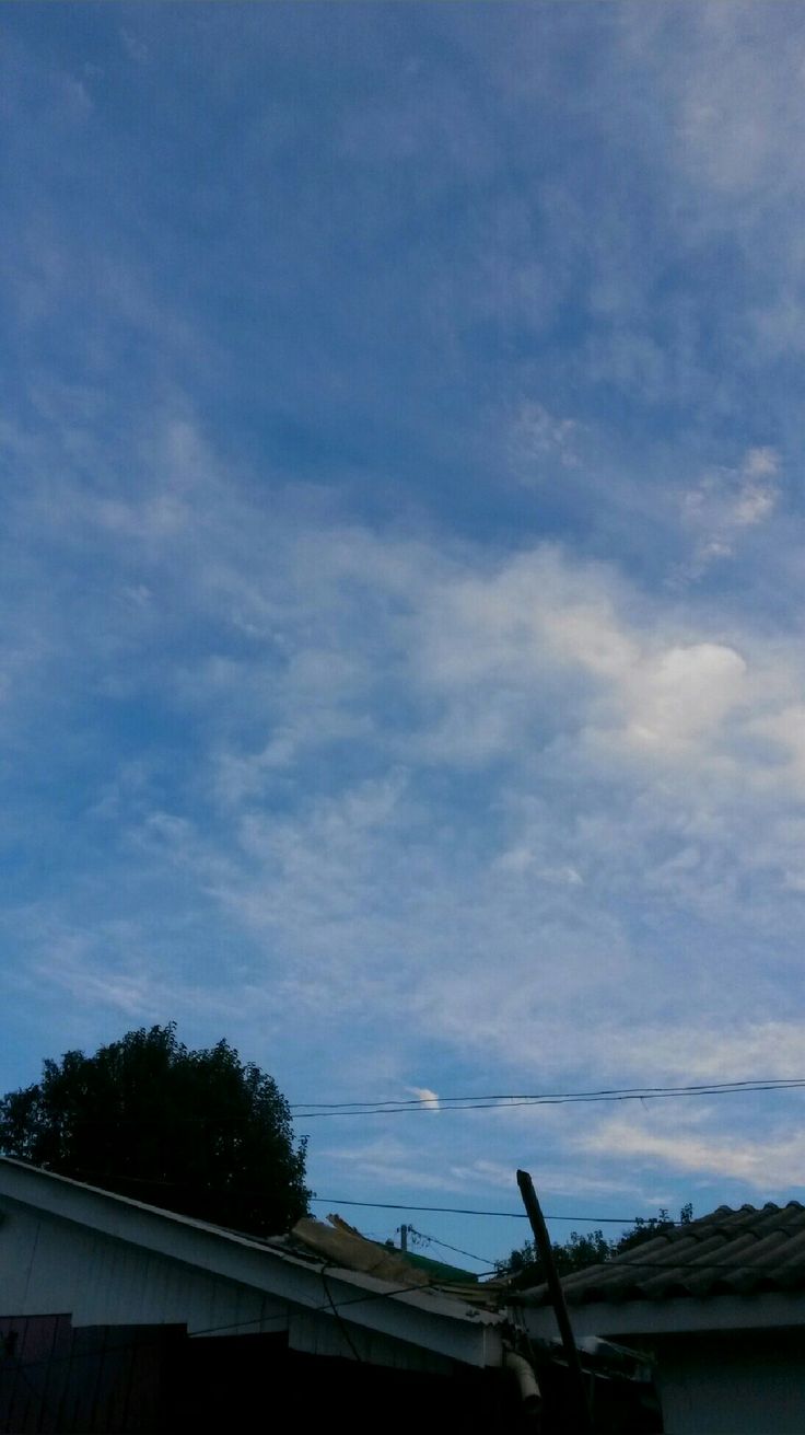 the sky is filled with clouds and some houses are in the foreground, one building has a clock on it