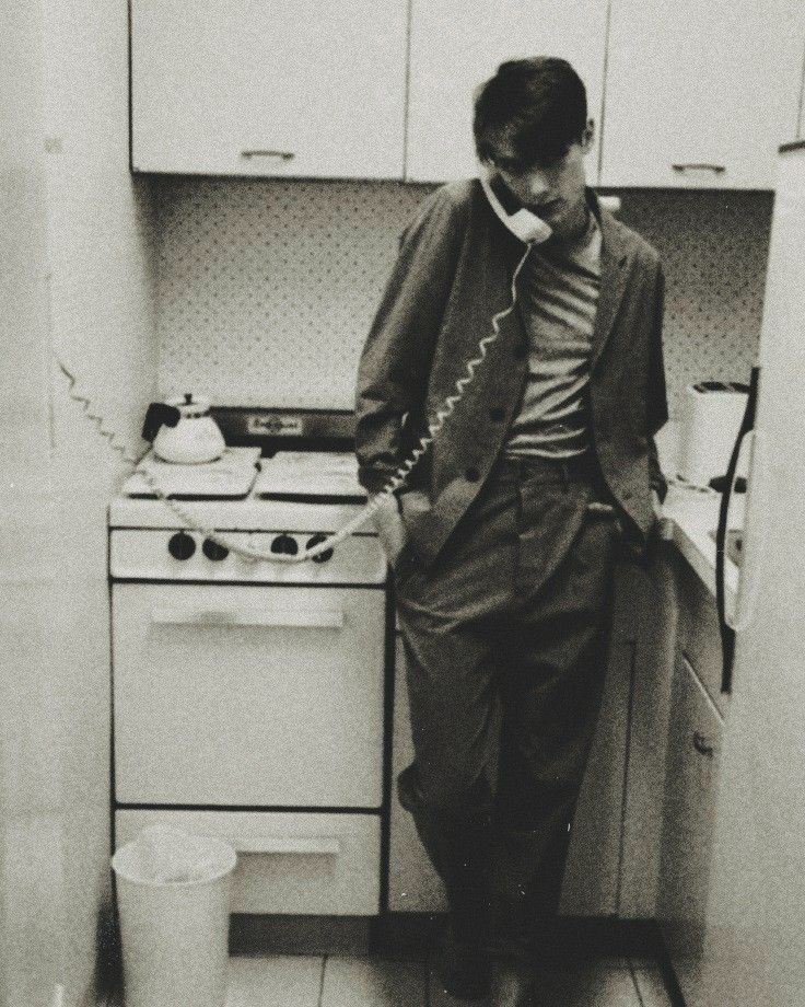 a man standing in a kitchen talking on a phone