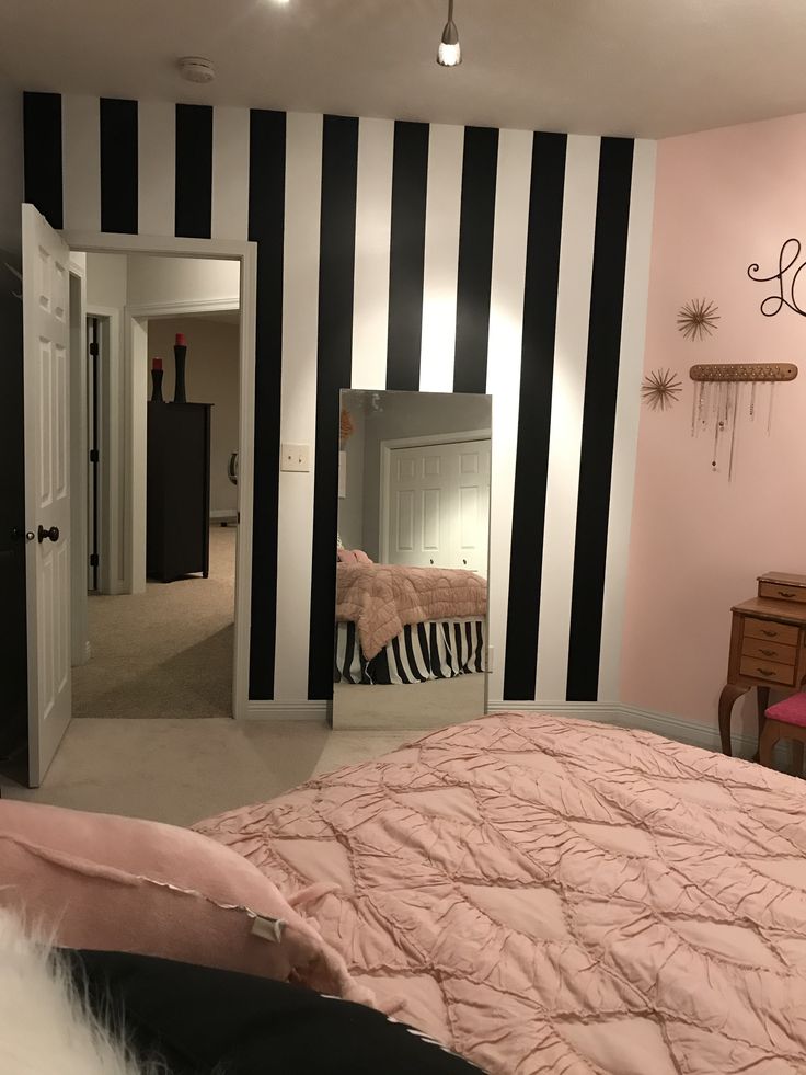 a bedroom with black and white stripes on the walls, pink bedding and a zebra print comforter