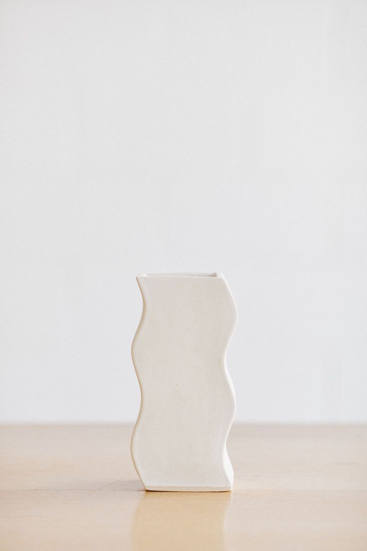 a white vase sitting on top of a wooden table