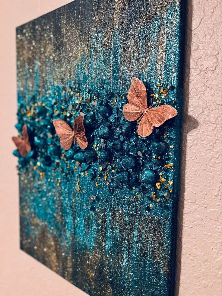 two butterflies on a blue and green painting with gold flecks in the background