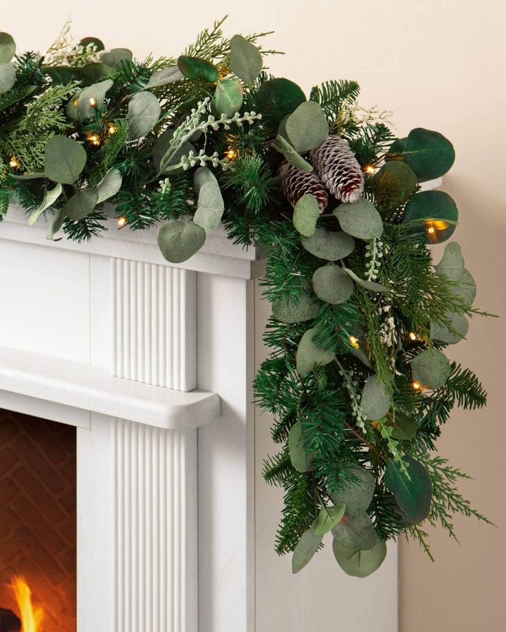 a fireplace decorated with greenery and pine cones