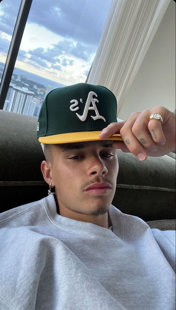 a man with a ring on his finger and wearing a baseball cap that says a's