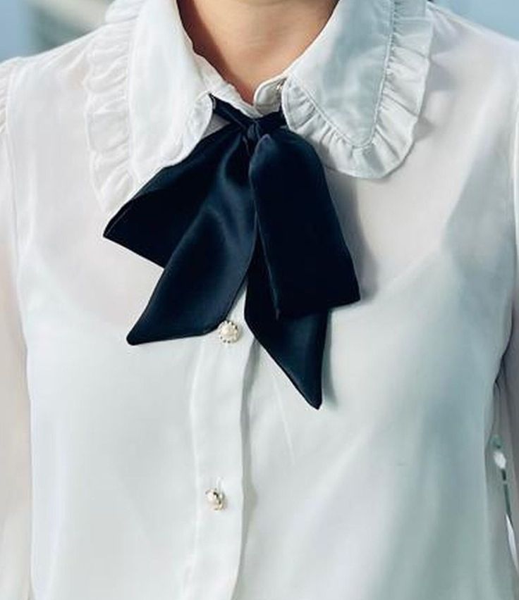 a woman wearing a white shirt with a black bow tie on her lapel neck