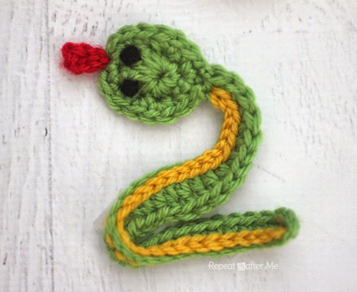 a crocheted snake with a red flower on it's head and tail