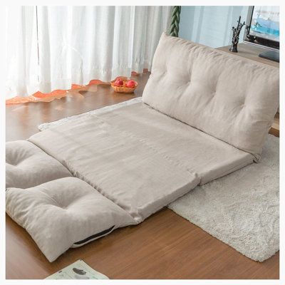 a futon bed sitting on top of a hard wood floor next to a window