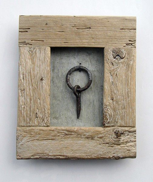 a wooden frame with a metal ring in the middle and a white wall behind it