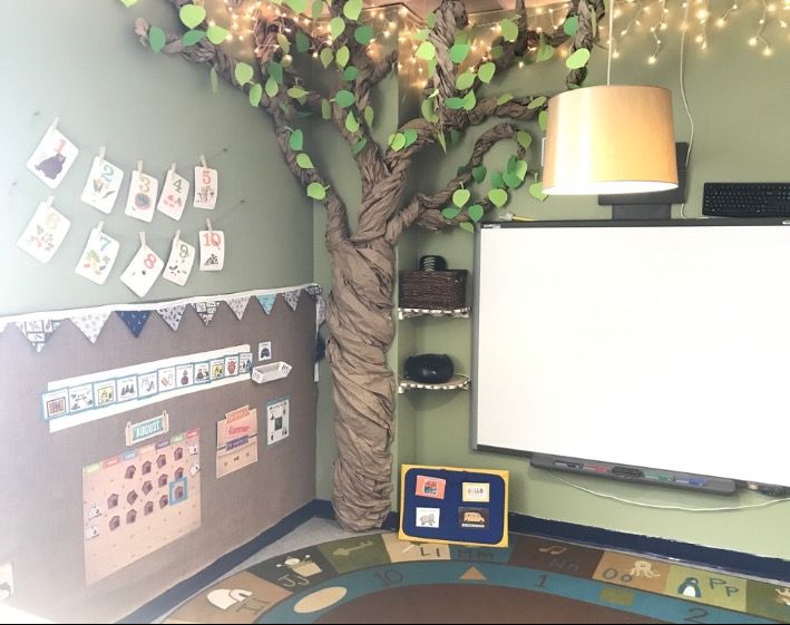 a classroom with a tree and bulletin board