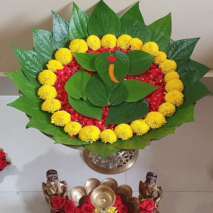 a vase filled with yellow and red flowers sitting on top of a table next to other decorations