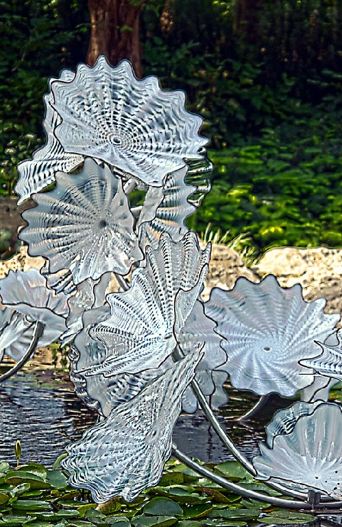 three glass flowers sitting on top of a body of water