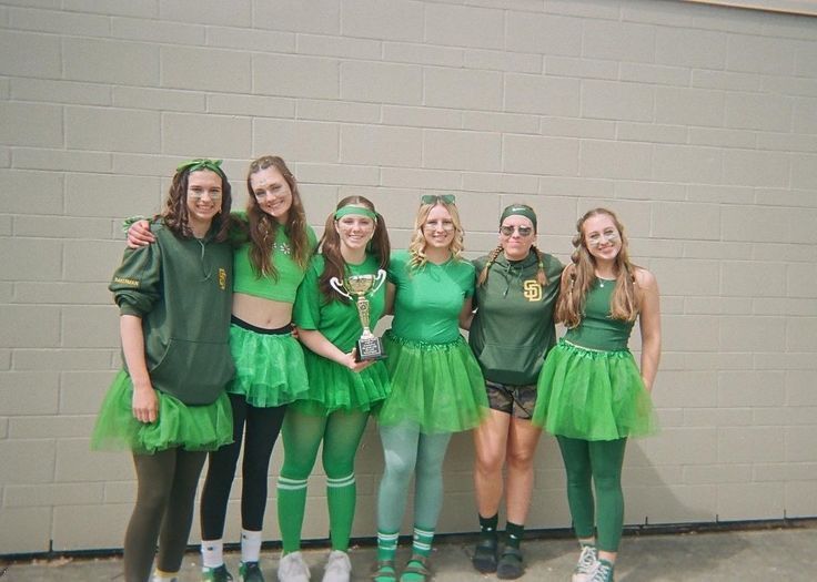 a group of girls dressed in green posing for the camera