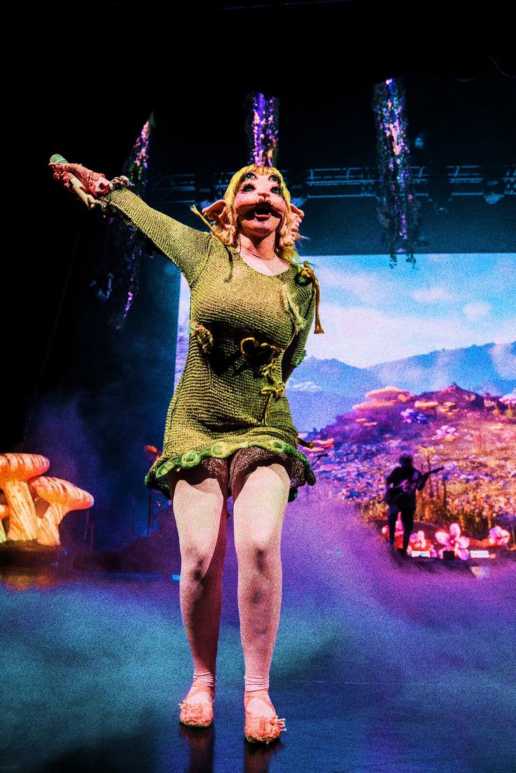 a woman is performing on stage with her hands in the air