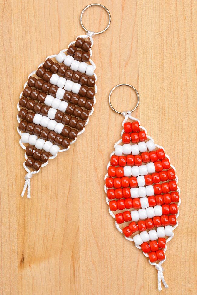 two beaded footballs are sitting on a wooden surface, one is brown and the other is white