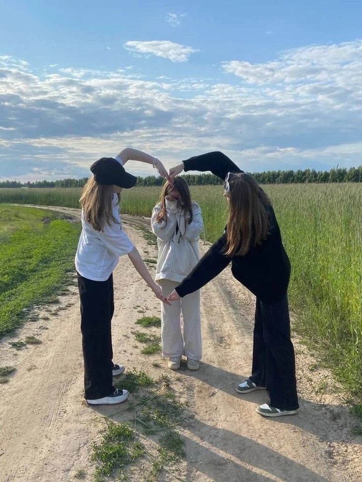 three girls standing on a dirt road holding hands