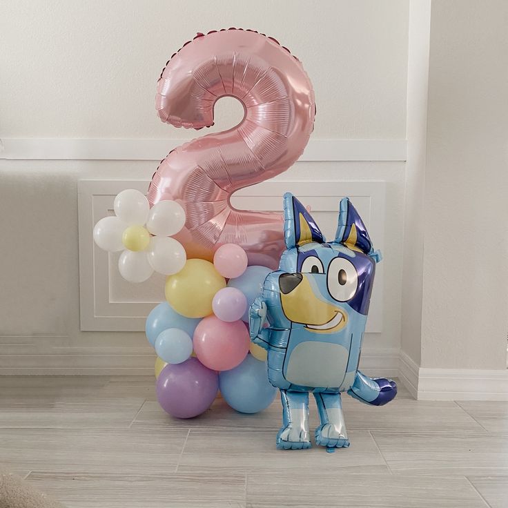 a balloon shaped like a dog standing next to balloons that spell out the number two