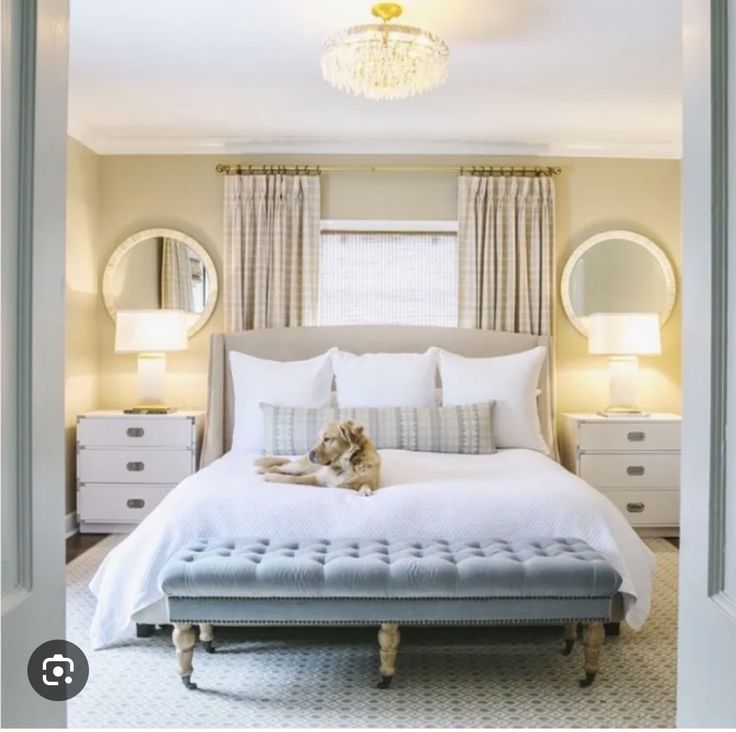 a white bed sitting under a chandelier in a bedroom