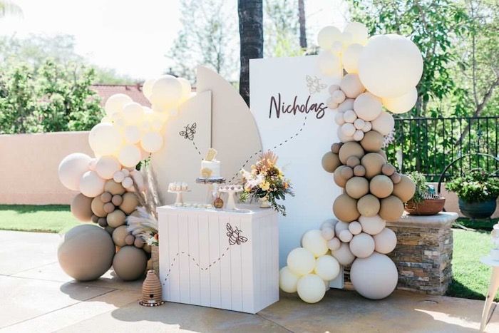 an outdoor wedding setup with balloons and decorations on the side of the aisle, including a sign that says nudges