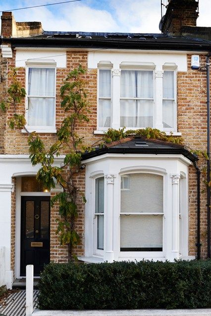 a brick house with white trim on the front and side windows, along with a black door