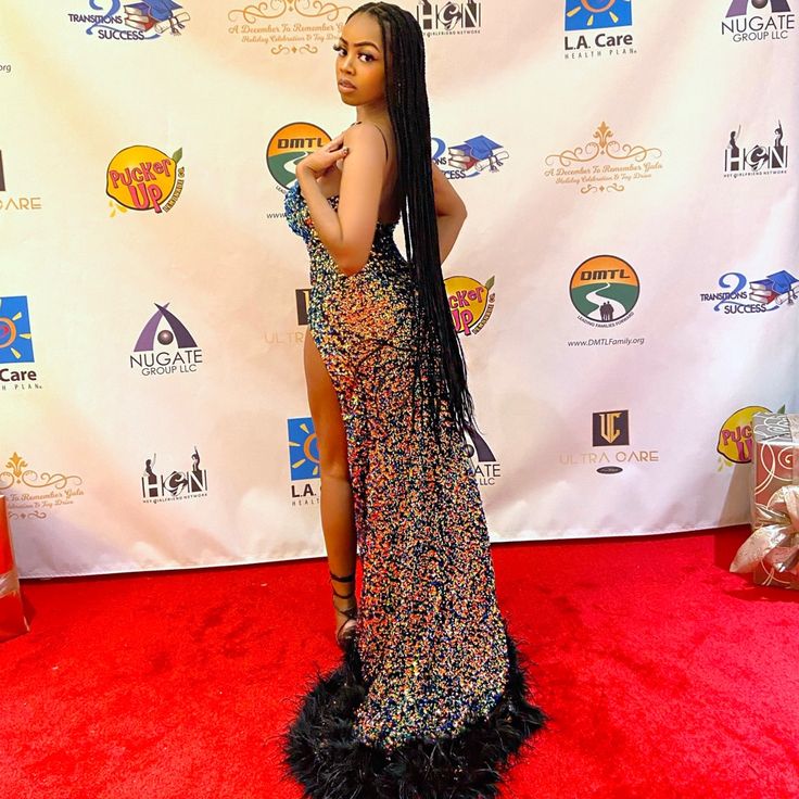 a woman standing on top of a red carpet in front of a white wall with an advertisement behind her