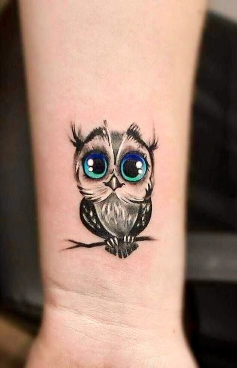 an owl with big blue eyes on the wrist is shown in this tattoo style photo