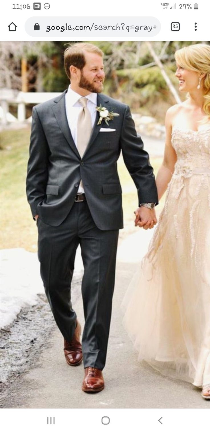 a man and woman are walking down the street holding hands while dressed in formal wear