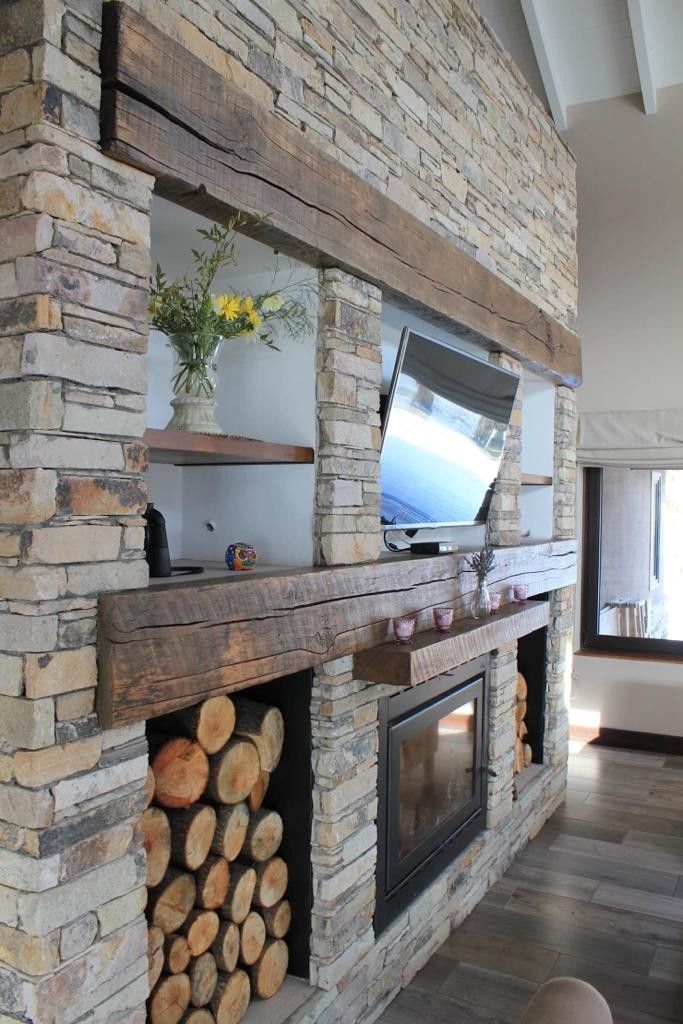 a fireplace with logs stacked on top of it and a tv mounted to the wall