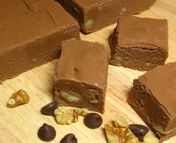 several pieces of chocolate cake sitting on top of a wooden cutting board with nuts scattered around it