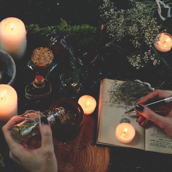 two people are sitting at a table with candles and an open book in front of them