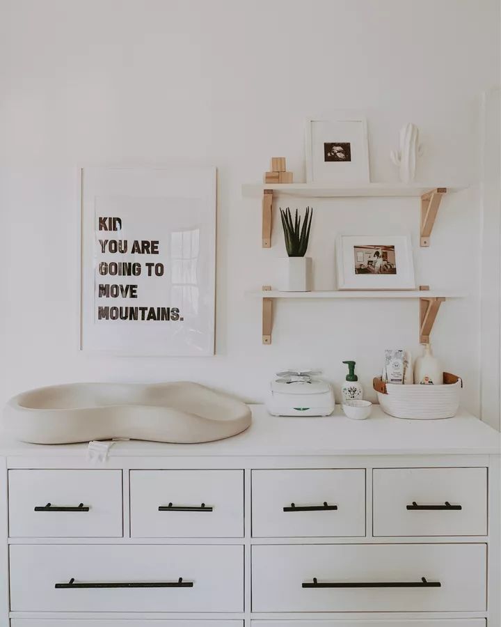 a white dresser topped with lots of drawers next to a shelf filled with pictures and other items