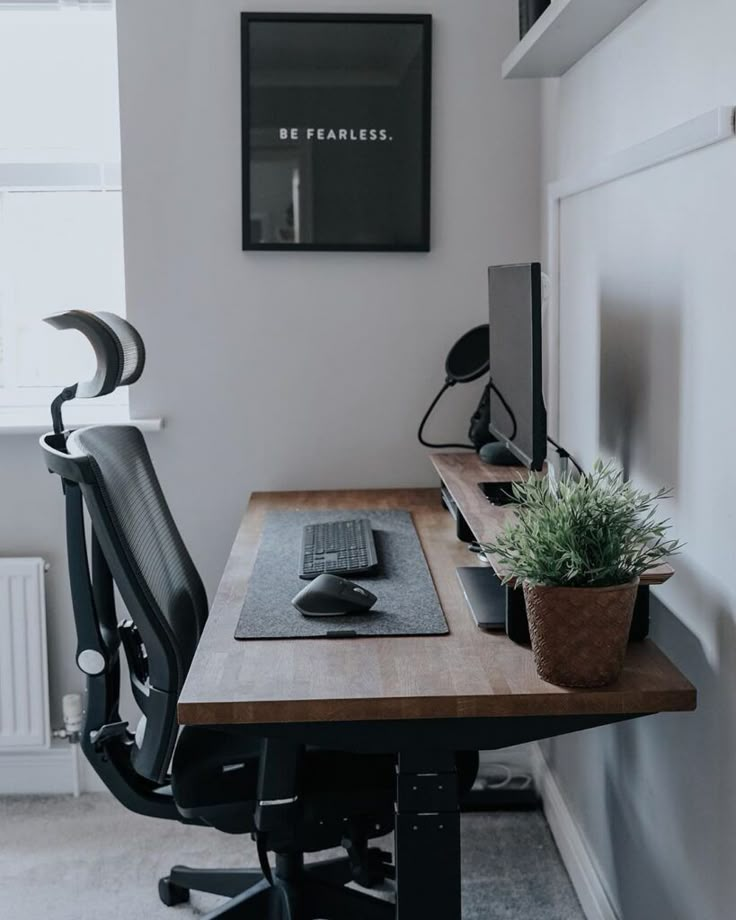 a desk with a computer on it and a potted plant in front of it