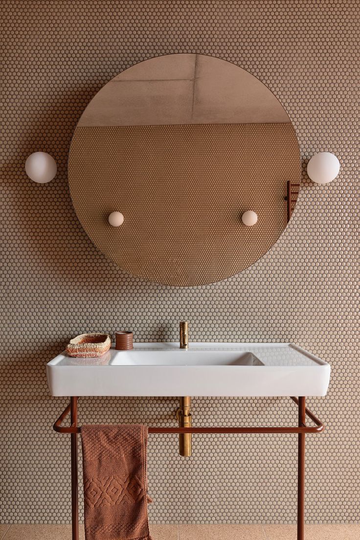 a white sink sitting under a mirror next to a wall mounted faucet in a bathroom