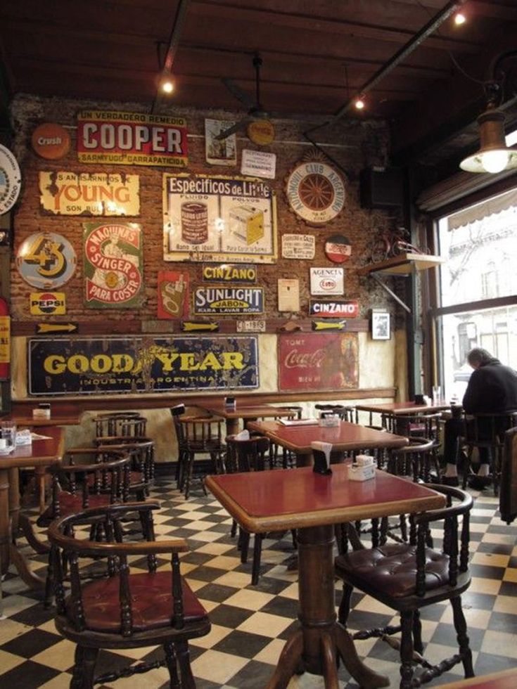 a restaurant with several tables and chairs in front of a large sign on the wall