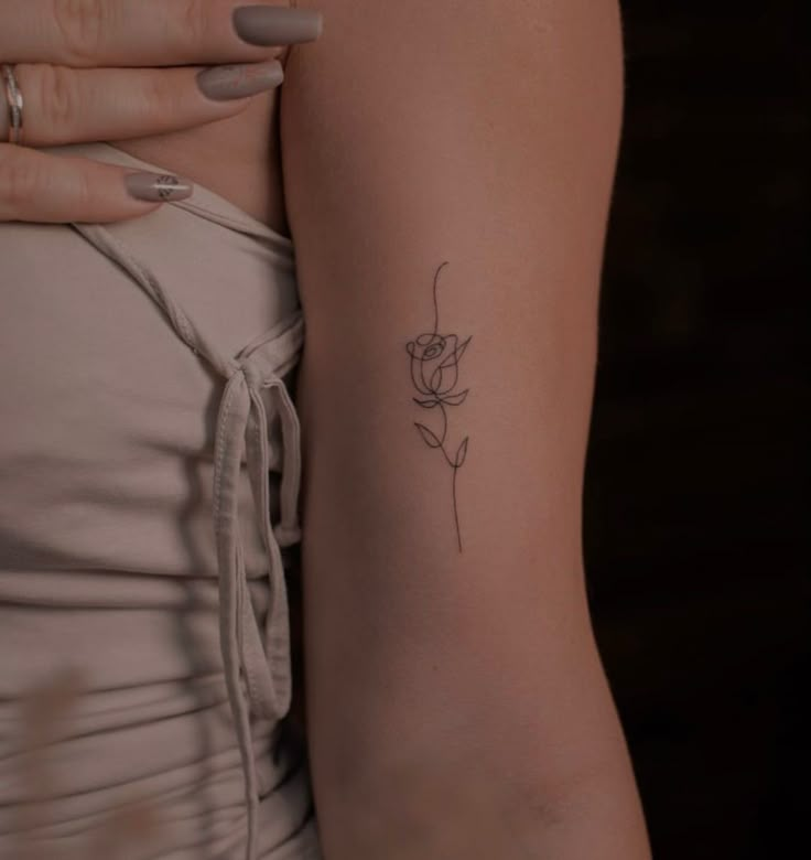 a woman's arm with a single rose tattoo on the left side of her right arm