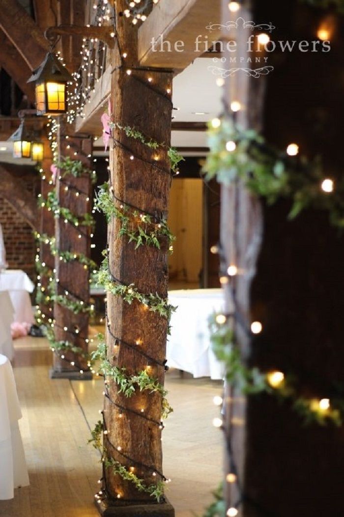 the wedding flowers are hanging from the wooden pillars in the ceremony room at the barn