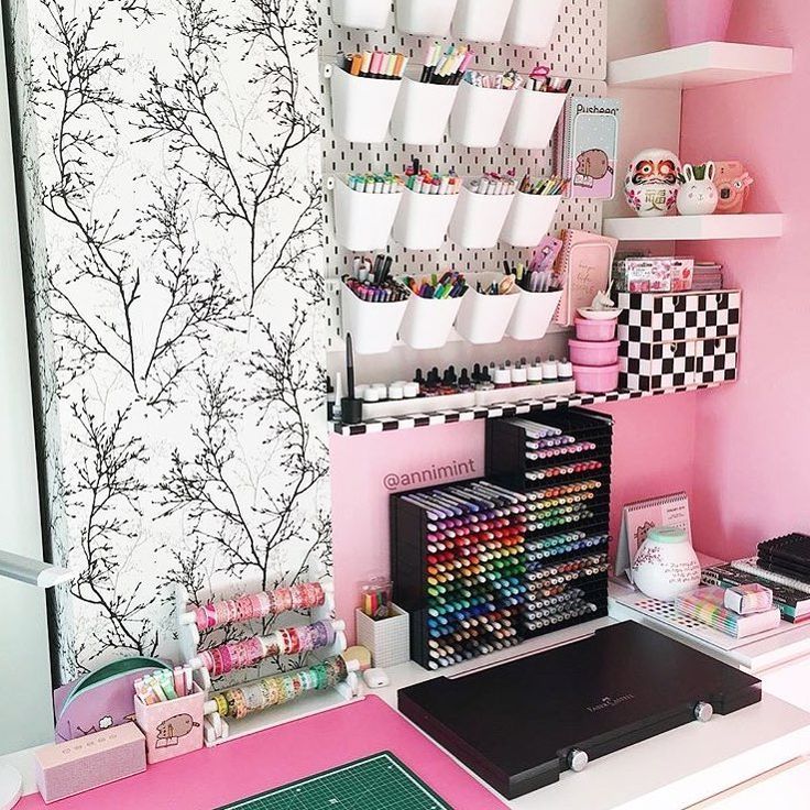 a pink desk with lots of crafting supplies on it and shelves above the desk