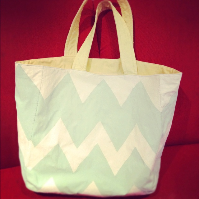 a white and green bag sitting on top of a red couch next to a wall