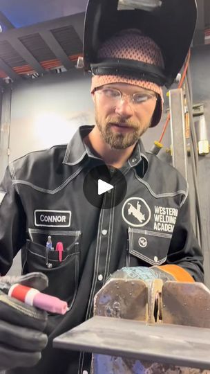 a man wearing a hat and glasses is working on something in a machine shop or workshop