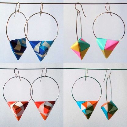 four different types of earrings hanging from clothes pins on a line, each with an origami design