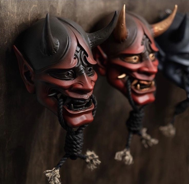 two red and black masks with horns hanging on a wall