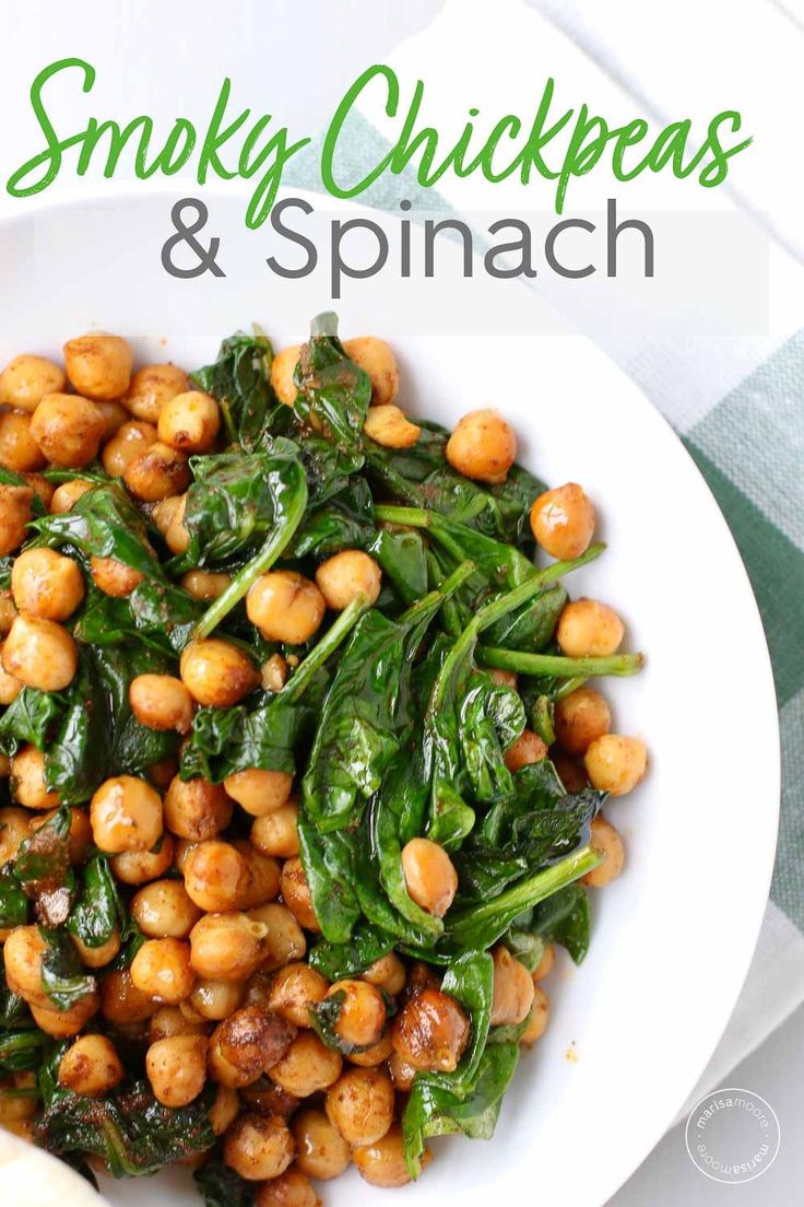 a white bowl filled with spinach and chickpeas on top of a table