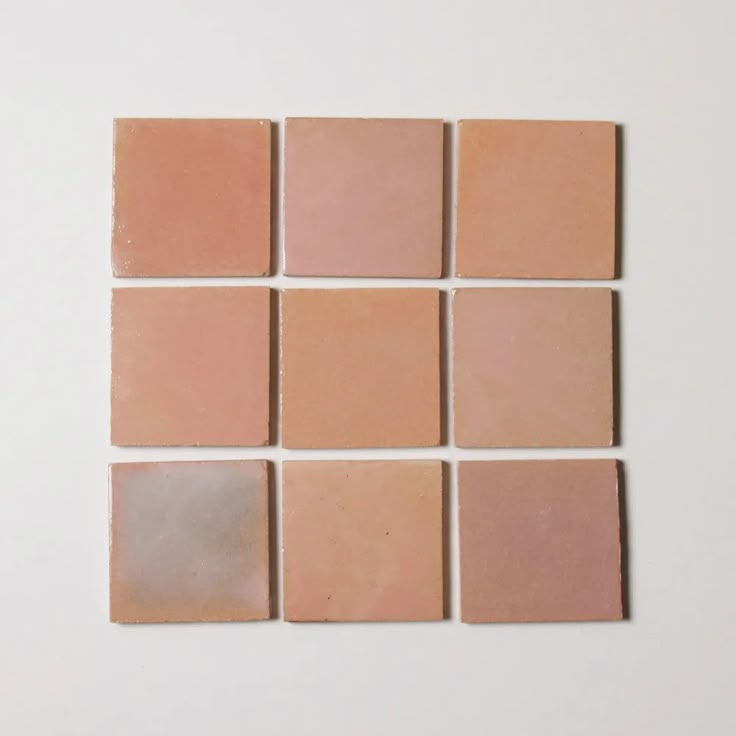 several different shades of pink and beige tile on a white surface, arranged in squares