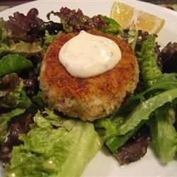 a white plate topped with lettuce and meat patties covered in ranch dressing