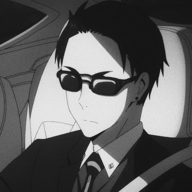 a man wearing sunglasses and a suit sitting in a car with his head turned to the side