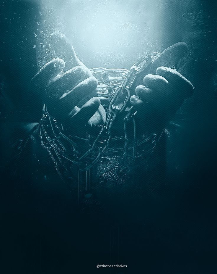 a person holding chains in their hands under water