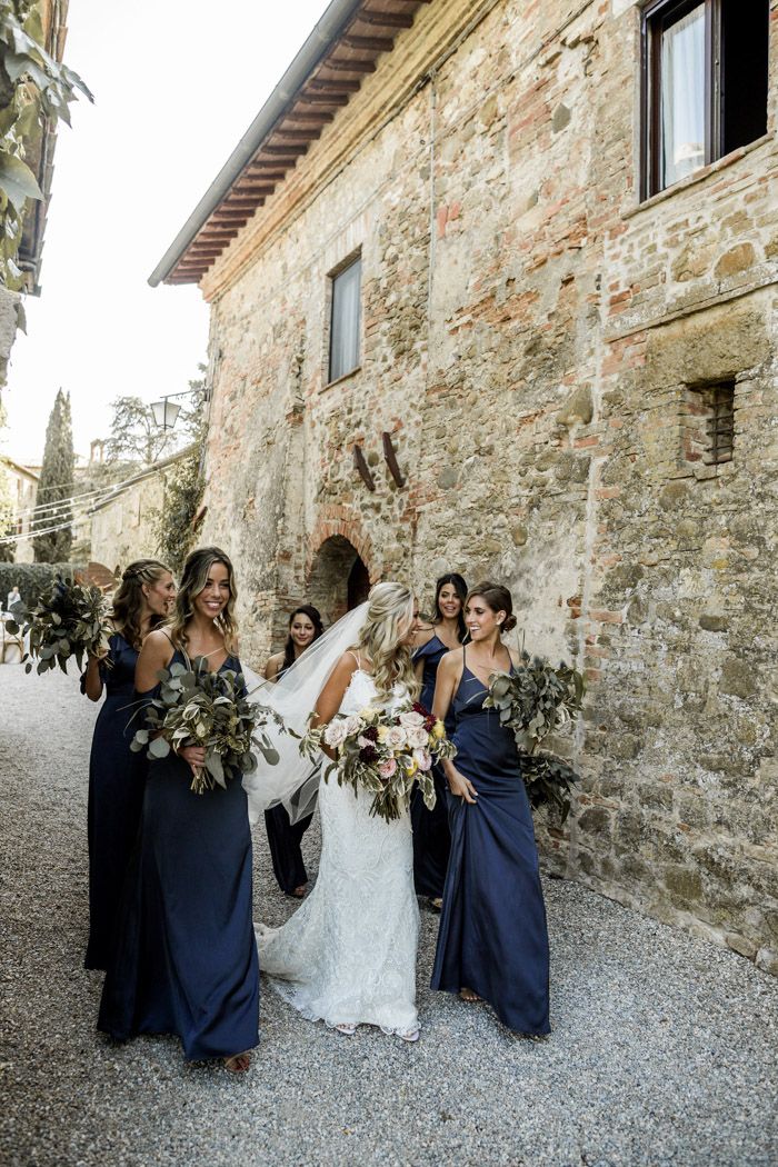 bride and her bridesmaids in front of an old stone building