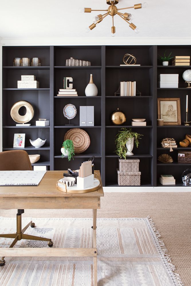 a living room filled with lots of bookshelves next to a desk and chair