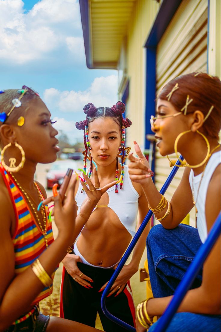 three young women standing next to each other in front of a building with their hands together